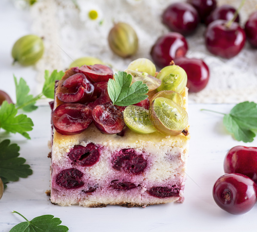 用白桌上的干酪樱桃和鹅莓做的蛋糕图片
