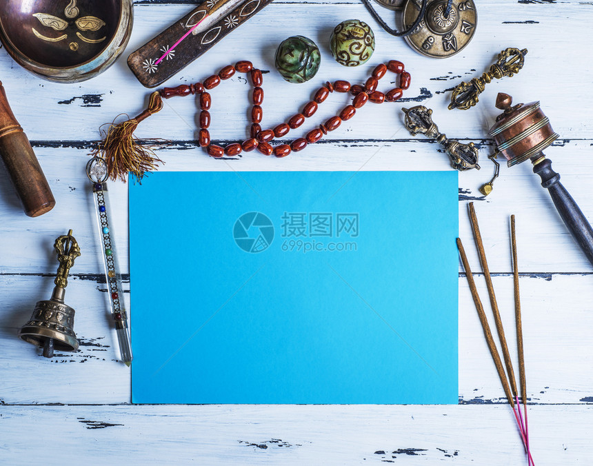 铜碗祈祷珠鼓石球和其他宗教物体用于冥想和替代药物放在一张空白纸蓝的中间图片