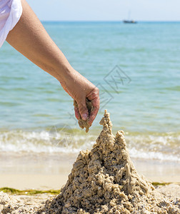 夏日用沙滩上的湿海建造一座城堡背景图片
