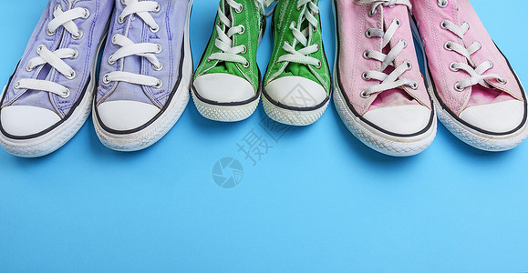 蓝色背景的三对旧式纺织运动鞋下面空间图片