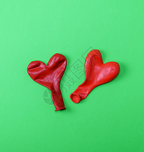 两颗红色橡胶气球以绿色背景的心形吹走两颗红橡胶气球图片