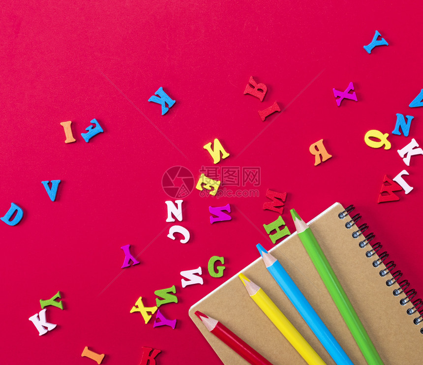 红色背景的多笔记本和多色木铅笔英文字母散图片