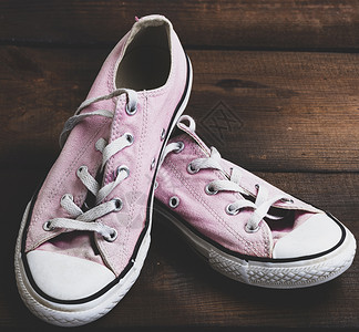 一对老式穿旧的粉色运动鞋在木背景上带白子旧式图片