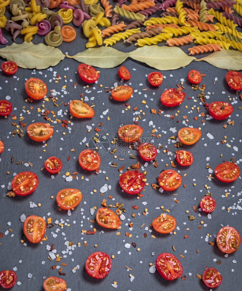 用面粉做的和切成一半的樱桃番茄加上盐和香料的意大利面饼螺旋状上升关闭图片