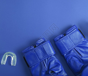 蓝皮革拳击手套和硅胶帽用于蓝底复制空间的牙齿图片