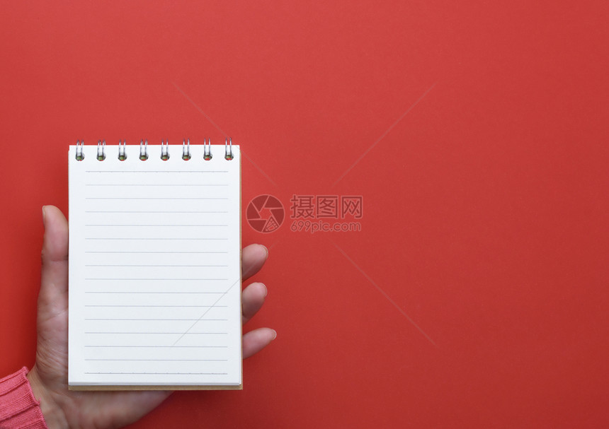 女手持张开的笔记本白页面红色背景复制空间图片