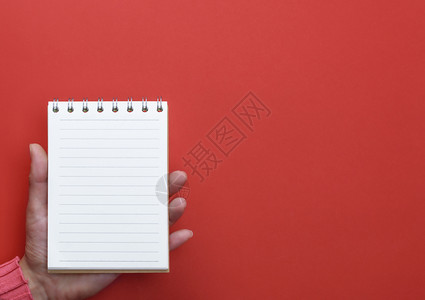 女手持张开的笔记本白页面红色背景复制空间图片