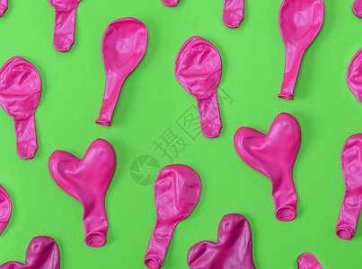 泄气绿色背景下许多被吹散的橡皮粉红色气球设计图片