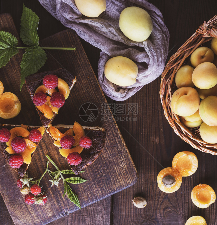三块芝士蛋糕杏子和草莓在木板上靠近新鲜水果顶端的景色图片