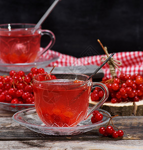 一个透明的杯子里热生茶手柄和碟子在灰色木制桌边新鲜浆果旁背景图片