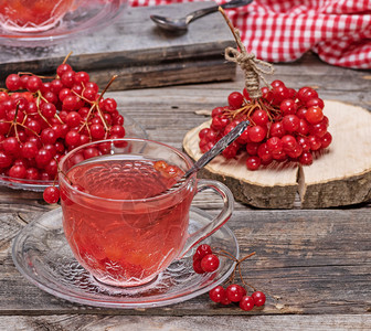 一个透明的杯子里热生茶手柄和碟子在灰色木制桌边新鲜浆果旁背景图片