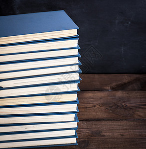 棕色木制桌子上蓝封面的大堆书复制空间背景图片