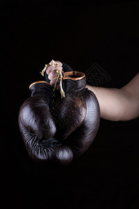 男人的手握着一双黑色的旧皮棕拳击手套图片