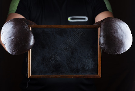 男子用棕色皮拳击手套握着一个空黑色框架复制空间图片