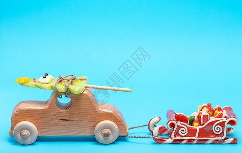 木童的汽车配有焦拉梅节的葡萄酒拉着雪橇蓝色背景的礼物图片