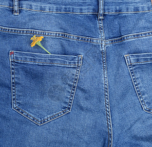 蓝色牛仔裤后口袋的黄色花朵关上图片