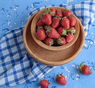 红色鲜草莓棕木制圆板蓝餐巾纸顶视图背景图片
