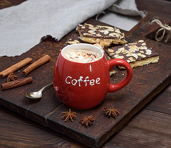 棕色板上一个红陶瓷杯子里有棉花糖的黑咖啡和杏仁加巧克力饼干图片