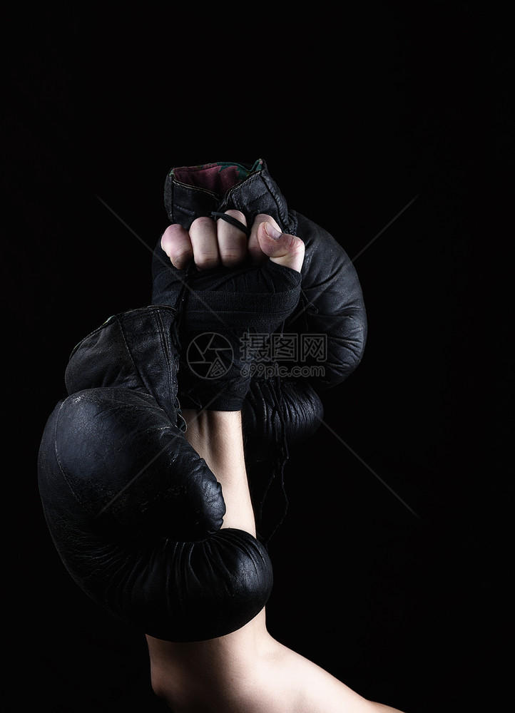 男人举起手来握着一副黑色皮拳击手套色背景图片