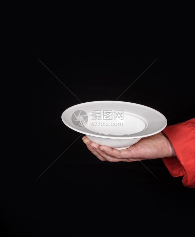 男手拿着黑色背景的空白陶瓷汤盘图片