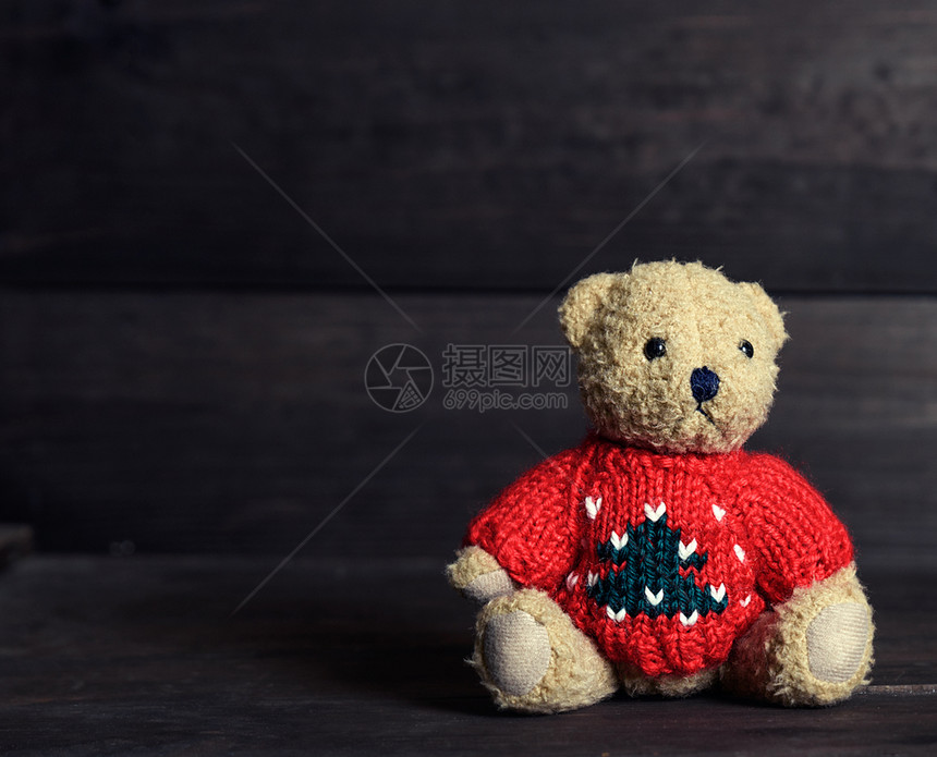 红毛衣的一只棕褐色老泰迪熊坐在木背景上复制空间图片