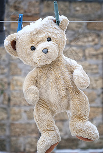 老泰迪熊挂在衣绳上寒雪的冬天图片