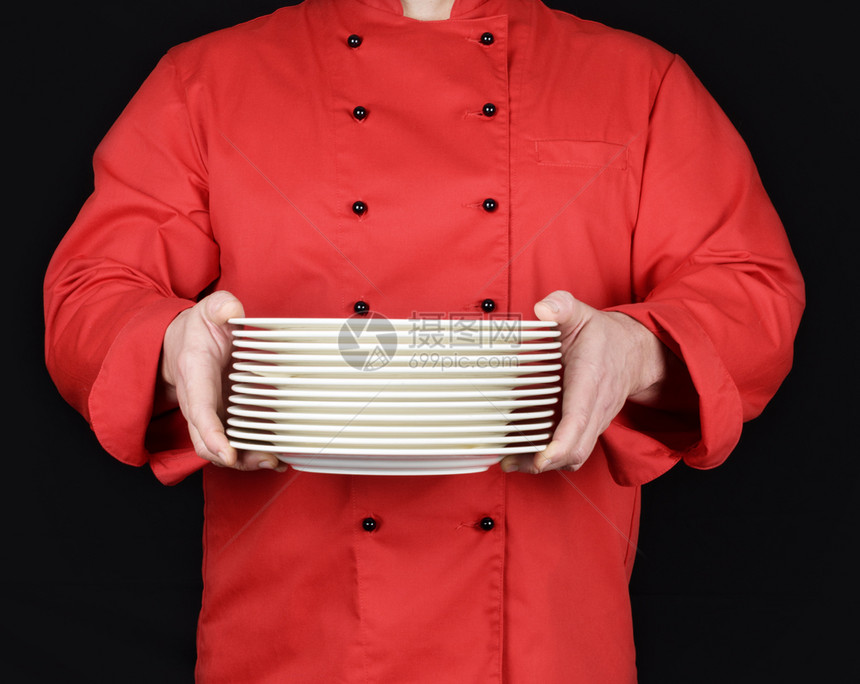 穿着红制服的厨师手里握着一堆圆白空盘子图片