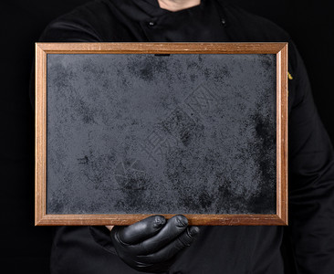 穿黑色制服和乳胶手套的厨师装黑色制服和乳胶手套装有空木板框复制间图片