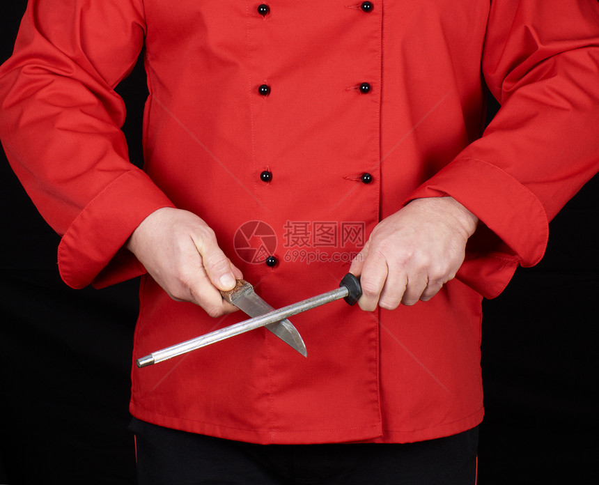 穿红制服的厨师磨利一把刀黑色背景的图片