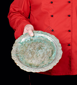 穿红制服的厨师手里拿着空铁圆盘黑色背景图片