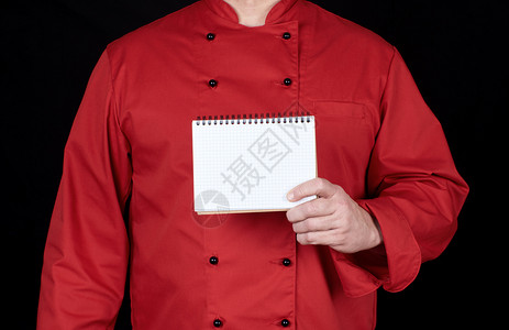 穿着红制服的厨师拿着空白笔记本黑色背景图片