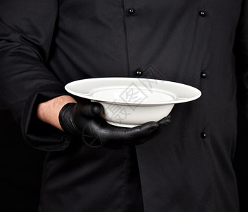 用黑色制服和乳胶手套煮衣和乳胶手套掌中握着一盘空的汤白图片