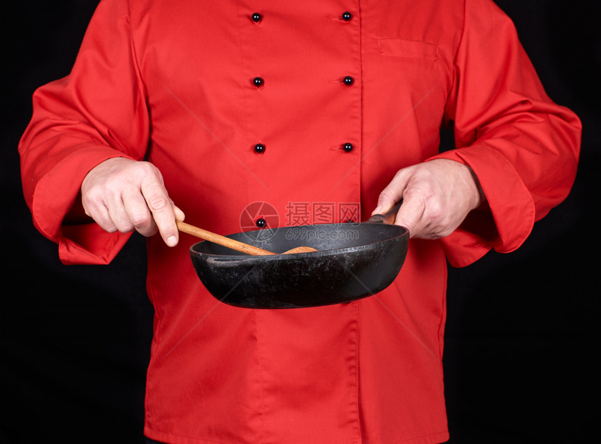 身穿红衣厨服手持空黑煎锅和底木勺图片