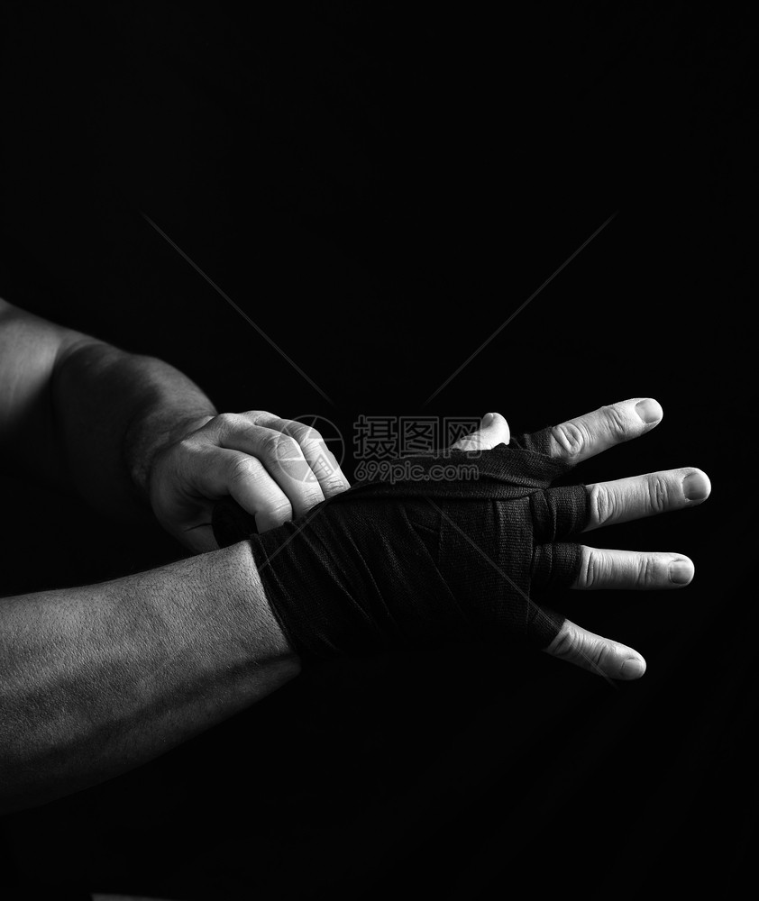 男人用黑色纺织绷带包着他的手用于运动黑色背景白的拖带图片