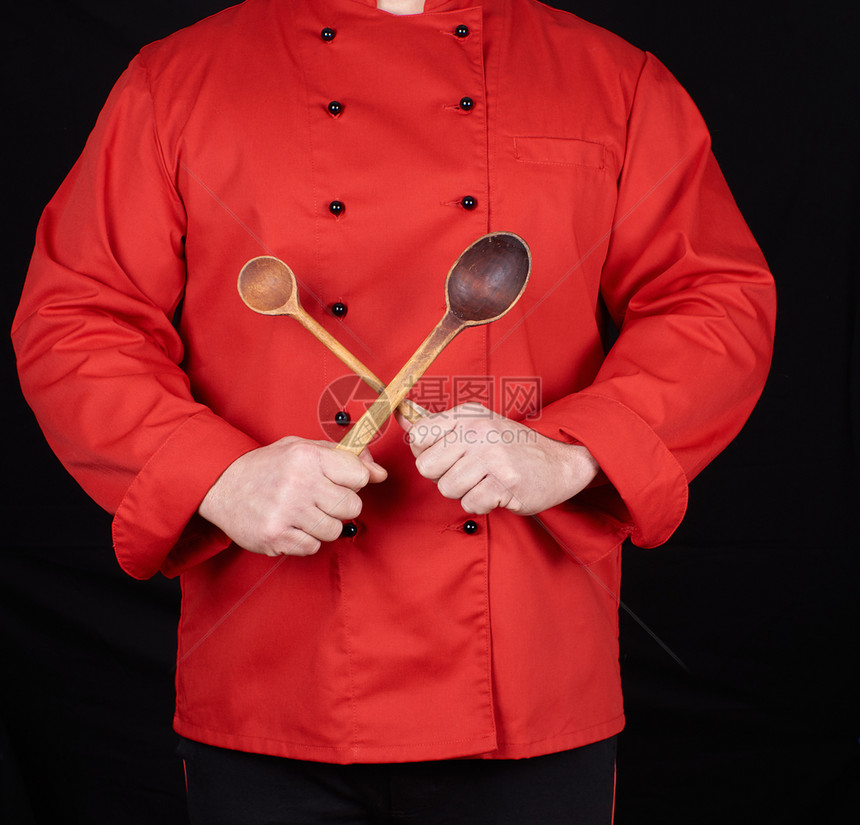 穿红制服的厨师拿着黑背景的旧木勺子图片