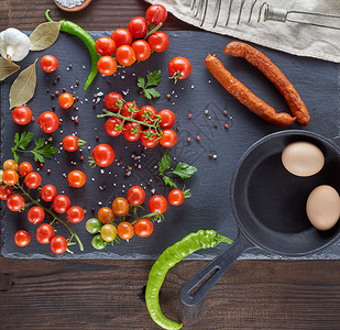 蛋壳新鲜红樱桃番茄和香肠炒鸡蛋的原料顶视图黑色背景图片