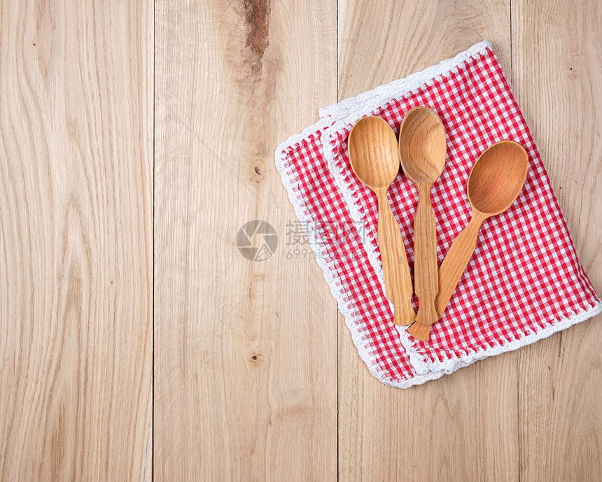 红色厨房毛巾上三个空木勺子复制空间图片