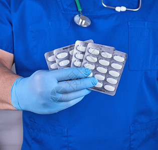 穿蓝制服的医生和带白药包装的消毒手套图片