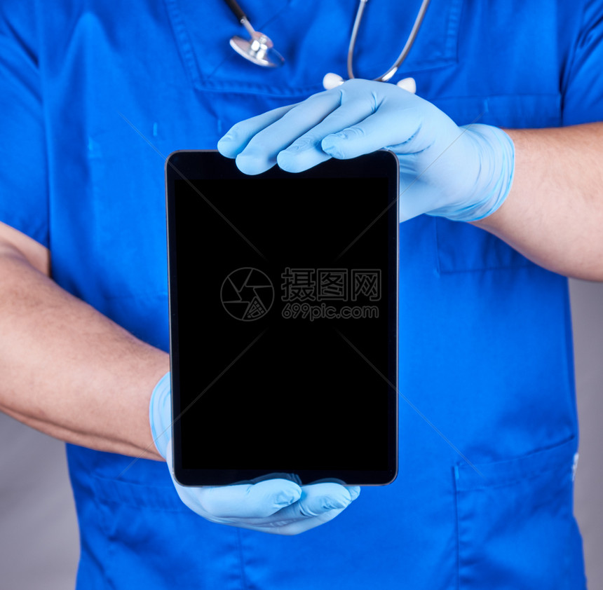 蓝制服医生和乳胶消毒手套持电子平板白黑屏幕灰色背景图片
