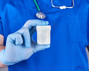 蓝制服医生和无菌乳胶手套装有塑料药丸包有选择地聚焦图片