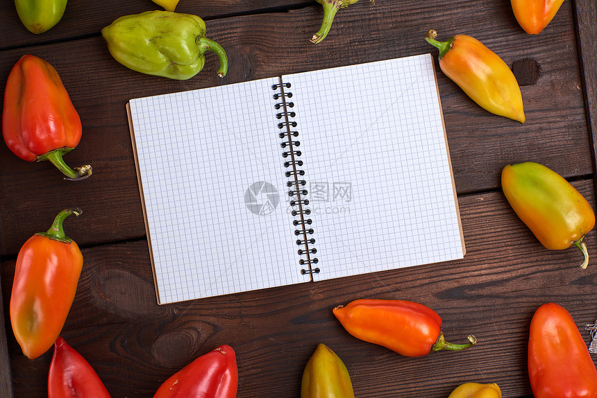 在新鲜胡椒蔬菜中棕色桌上的白纸笔图片