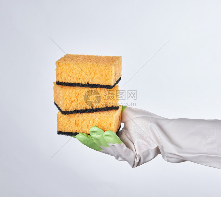 手套握着黄色的厨房海绵白色背景图片