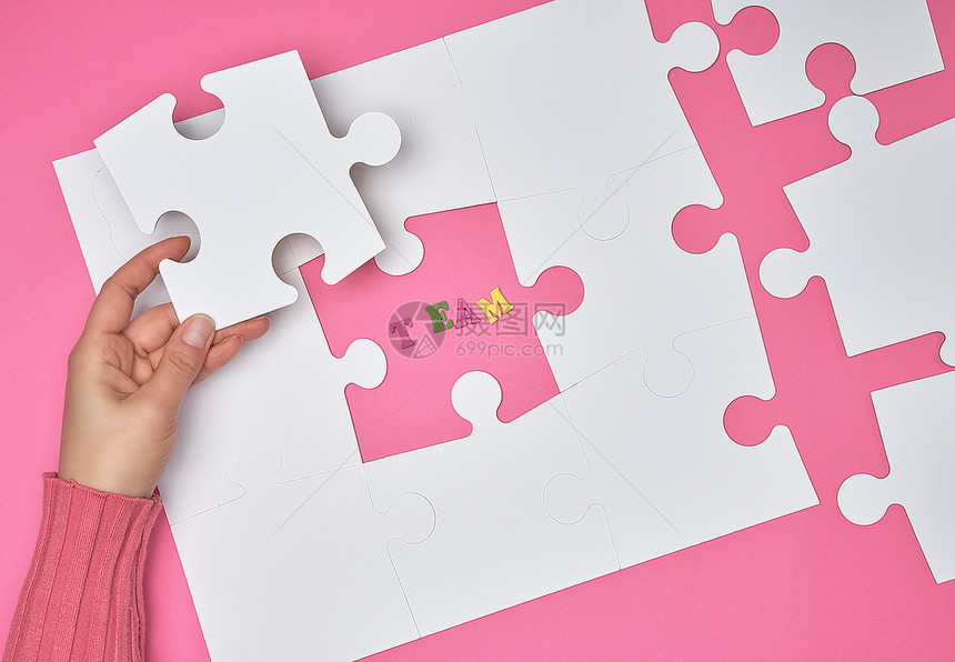 女手在粉红色背景即注册团队上画了白色大谜题公司招聘的概念图片