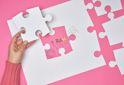女手在粉红色背景即注册团队上画了白色大谜题公司招聘的概念图片