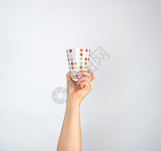 白色背景的女子手掌中带有多色圆形的陶瓷杯将手举起来图片