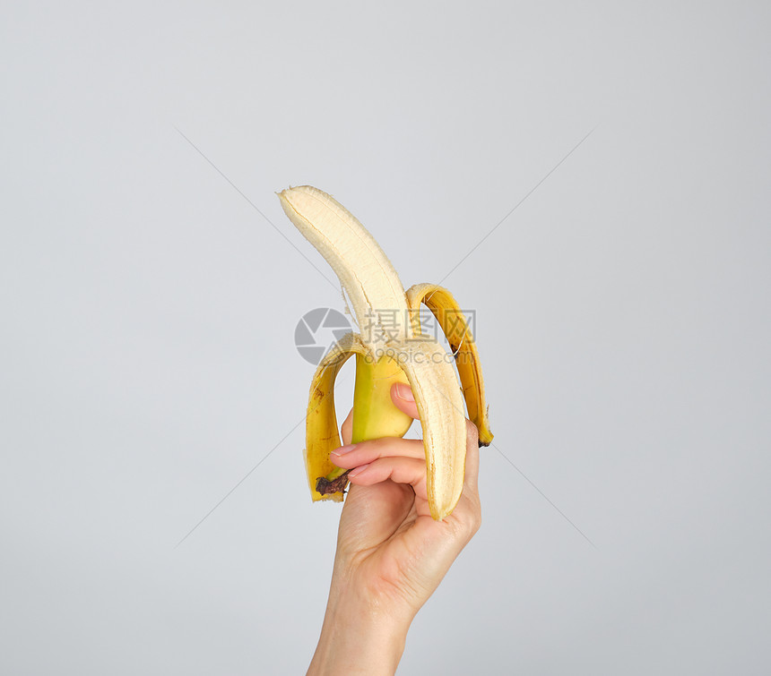 白色背景的女手上新鲜香蕉皮图片
