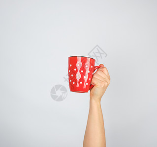 白色背景的女用手红陶瓷杯举起手来图片