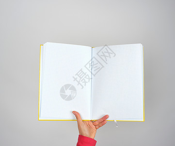 女手握着张开的黄色笔记板在一个灰色背景的单元格中复制空图片