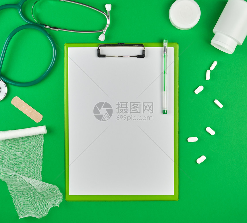 在绿色背景顶视图写处方的空间带有白片医学听诊器药片和纺织品绷带的纸持有者图片