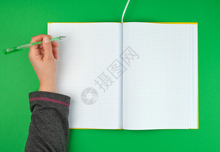 女手握笔接近空开记本在细胞中绿色背景顶视图图片